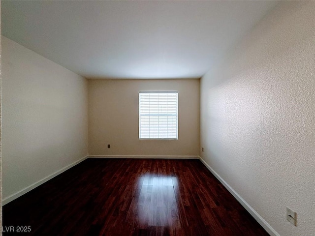 unfurnished room with baseboards and dark wood-type flooring