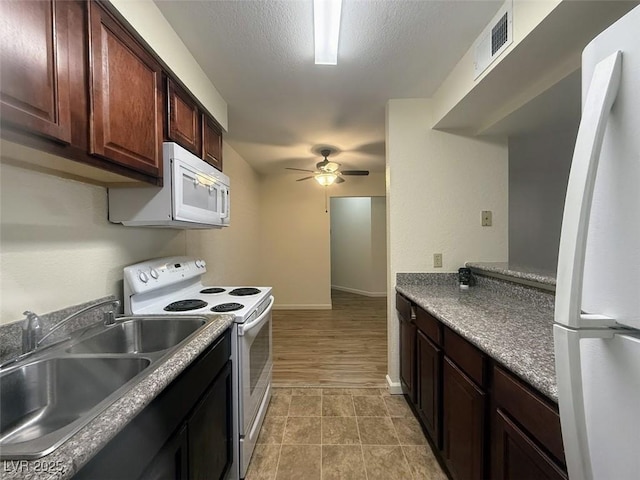 kitchen featuring a sink, ceiling fan, visible vents, baseboards, and white appliances
