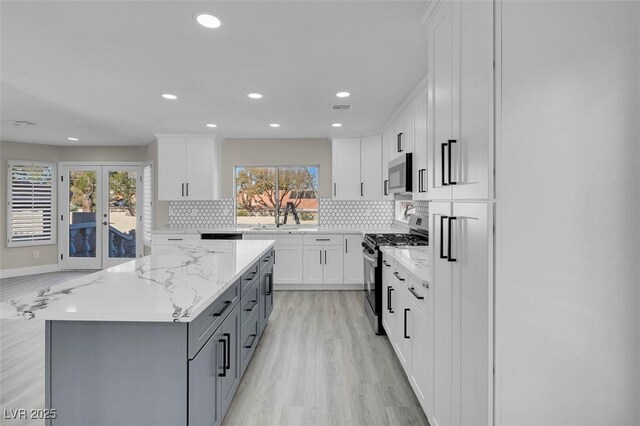 8232 Ocean Terrace Way, Las Vegas, NV 89128 - kitchen featuring gray cabinets, light wood-style flooring, appliances with stainless steel finishes, backsplash, and a center island
