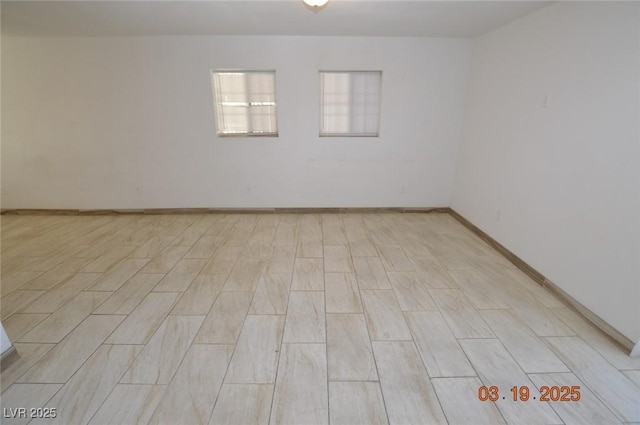 spare room with baseboards and light wood finished floors
