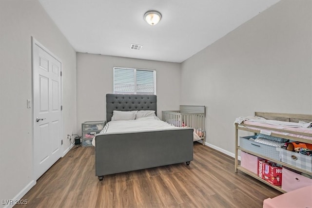 bedroom with visible vents, wood finished floors, and baseboards