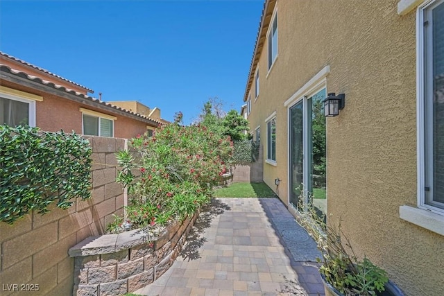 view of side of home featuring a patio, a fenced backyard, and stucco siding
