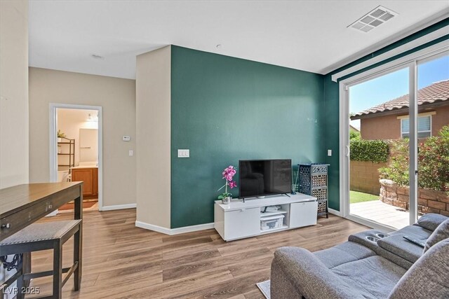 living area featuring wood finished floors, visible vents, and baseboards
