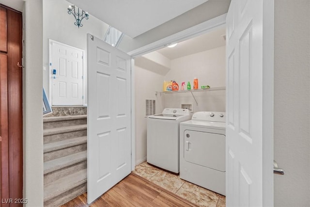 laundry room featuring separate washer and dryer, visible vents, light wood-style flooring, and laundry area