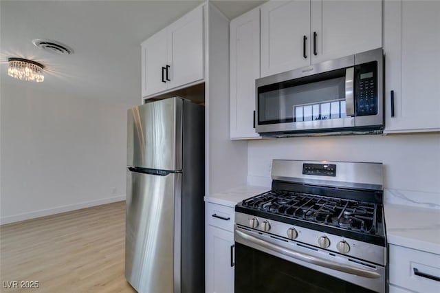 kitchen featuring visible vents, light wood-style flooring, stainless steel appliances, and white cabinetry
