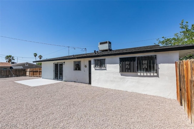 rear view of property with a patio, fence, central AC unit, and stucco siding