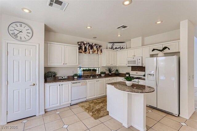 kitchen featuring dark stone counters, visible vents, white cabinetry, and white appliances