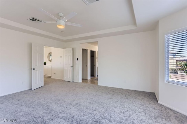 unfurnished bedroom featuring a raised ceiling, visible vents, ceiling fan, and light colored carpet