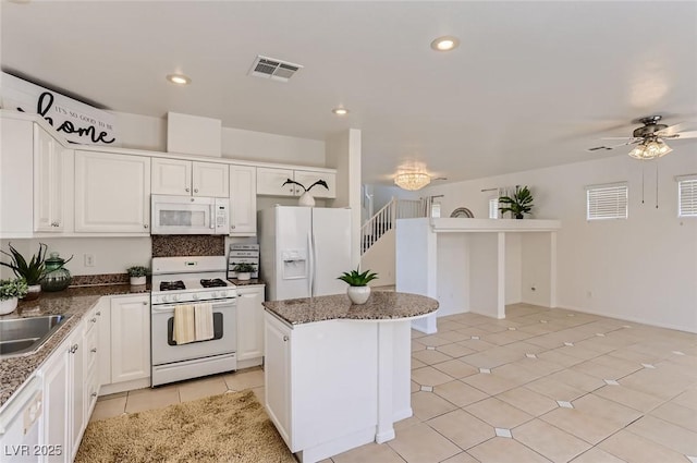 kitchen with white cabinets, visible vents, ceiling fan, a center island, and white appliances