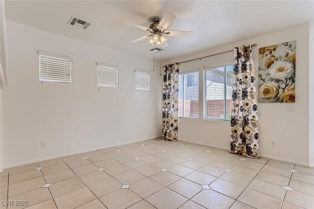 empty room with baseboards, visible vents, light tile patterned floors, and ceiling fan