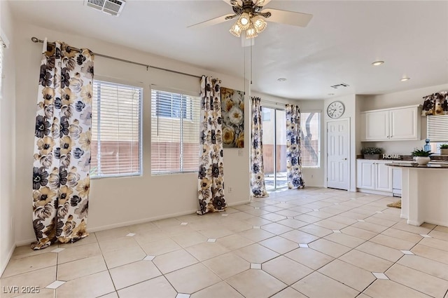 unfurnished dining area with ceiling fan, visible vents, a healthy amount of sunlight, and baseboards