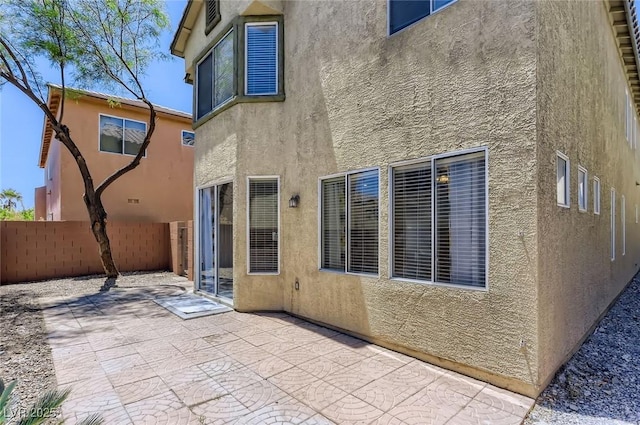 rear view of house featuring a patio, stucco siding, and fence