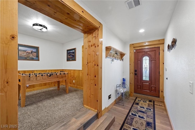 entryway with visible vents, wainscoting, wood finished floors, baseboards, and wooden walls