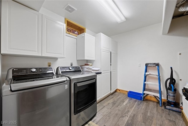 washroom featuring cabinet space, independent washer and dryer, light wood-style flooring, baseboards, and visible vents