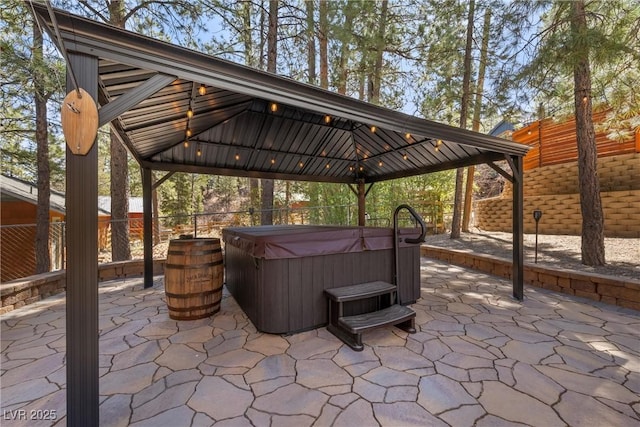 view of patio with a hot tub, a gazebo, and fence