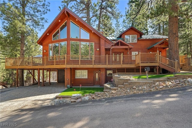 exterior space with driveway, a wooden deck, metal roof, and a carport