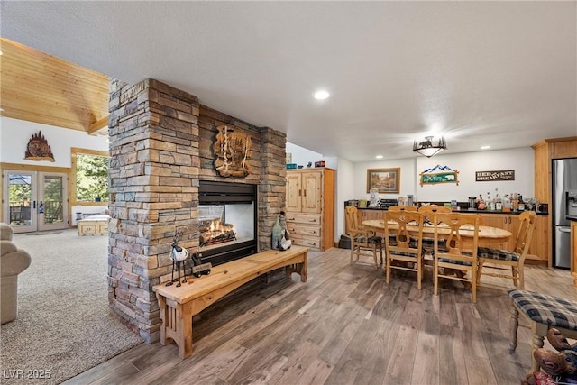 dining room with french doors, a dry bar, a fireplace, wood finished floors, and recessed lighting