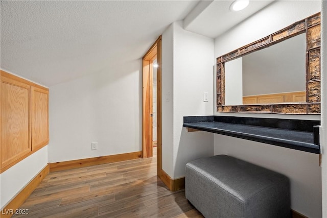 hall featuring baseboards, a textured ceiling, and wood finished floors