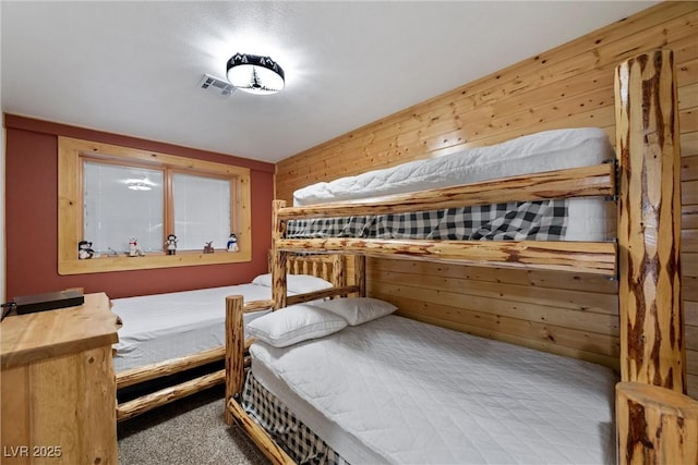 carpeted bedroom featuring visible vents and wood walls