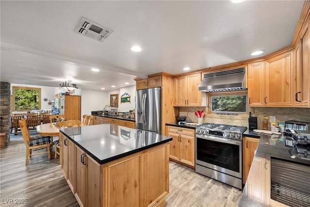 kitchen with visible vents, dark countertops, appliances with stainless steel finishes, extractor fan, and light wood-style flooring