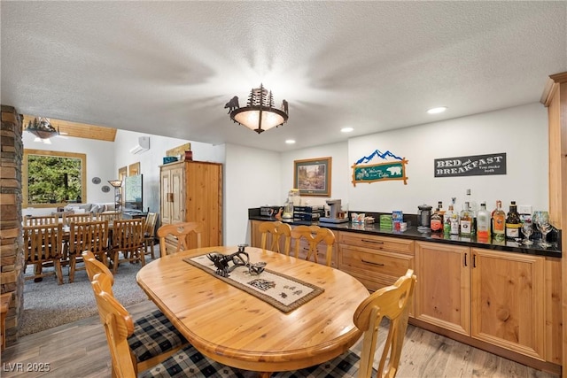 dining room with recessed lighting, a textured ceiling, and light wood-style flooring