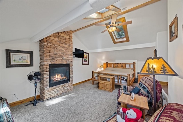 bedroom featuring carpet flooring, ceiling fan, a stone fireplace, baseboards, and lofted ceiling with skylight