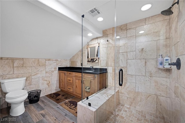 bathroom featuring visible vents, tile walls, a stall shower, vanity, and toilet