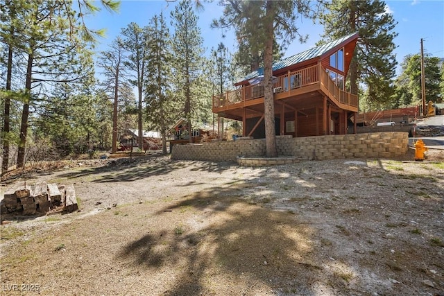rear view of house featuring a standing seam roof, a wooden deck, and metal roof