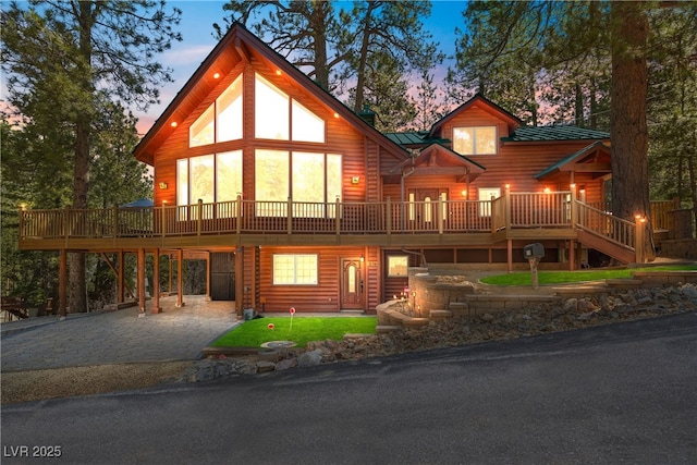 view of front of house with driveway, a wooden deck, metal roof, and a carport