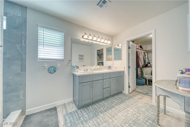 full bathroom featuring visible vents, wood finished floors, double vanity, and a sink