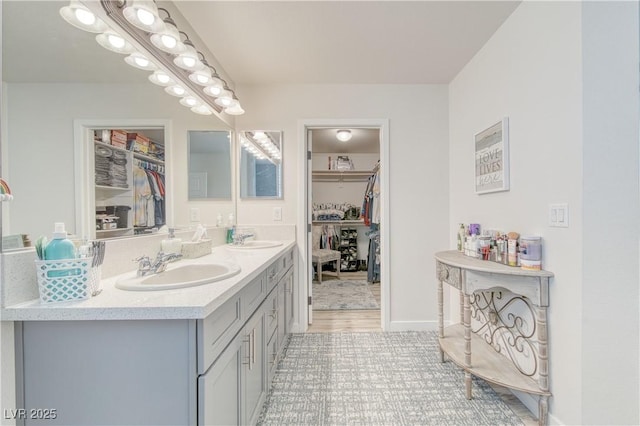 full bathroom with double vanity, a walk in closet, and a sink