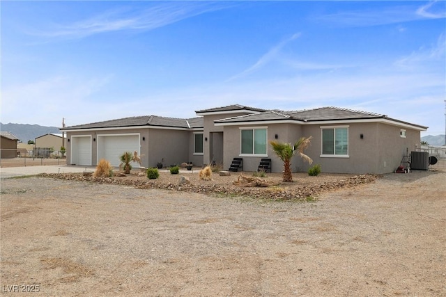 3660 Stirrup, Pahrump, NV 89048 - view of front of house featuring driveway, stucco siding, central air condition unit, an attached garage, and fence