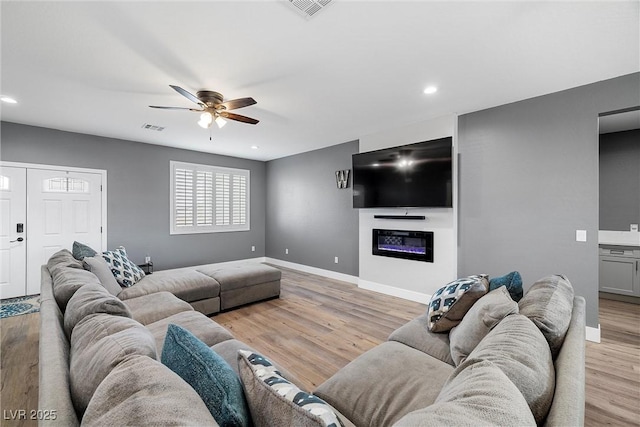 3660 Stirrup, Pahrump, NV 89048 - living room featuring visible vents, ceiling fan, light wood-style floors, and a glass covered fireplace