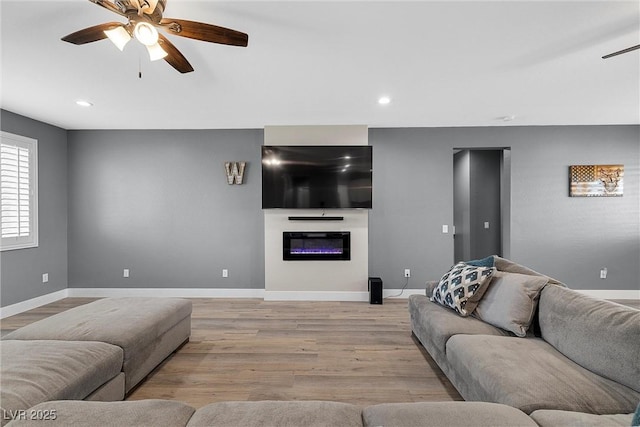 3660 Stirrup, Pahrump, NV 89048 - living area with light wood finished floors, recessed lighting, a glass covered fireplace, a ceiling fan, and baseboards