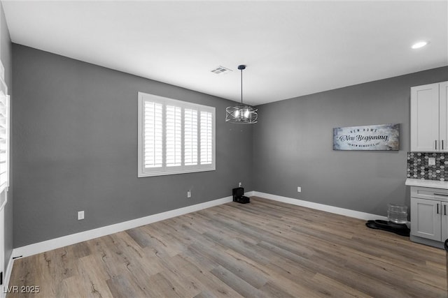 3660 Stirrup, Pahrump, NV 89048 - unfurnished dining area featuring an inviting chandelier, wood finished floors, visible vents, and baseboards