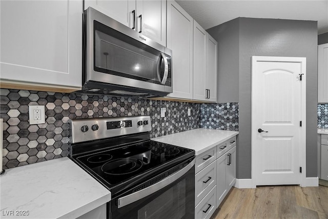 3660 Stirrup, Pahrump, NV 89048 - kitchen featuring stainless steel microwave, range with electric cooktop, backsplash, white cabinetry, and light wood-style flooring