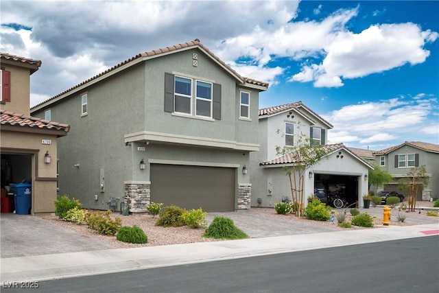 mediterranean / spanish-style house featuring driveway, a tile roof, an attached garage, stone siding, and stucco siding