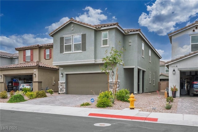 view of front facade with stucco siding, an attached garage, decorative driveway, and a tiled roof