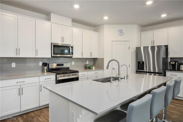 kitchen with a sink, a kitchen island with sink, dark wood finished floors, stainless steel appliances, and recessed lighting