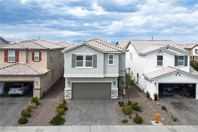 view of front of home featuring decorative driveway, an attached garage, stone siding, and stucco siding