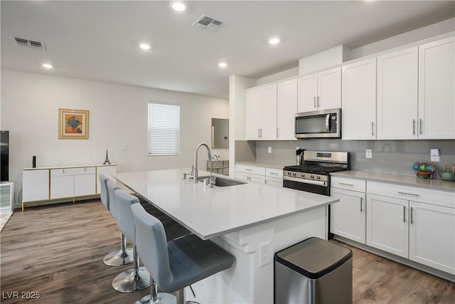 kitchen with visible vents, a sink, wood finished floors, and stainless steel appliances