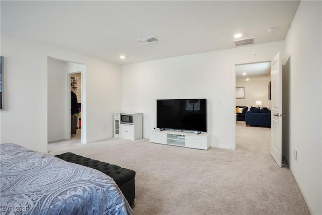 carpeted bedroom featuring recessed lighting, baseboards, visible vents, and a walk in closet