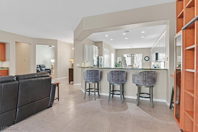 2132 Twin Falls Dr, Henderson, NV 89044 - kitchen with a kitchen bar, refrigerator, open floor plan, light tile patterned floors, and a peninsula