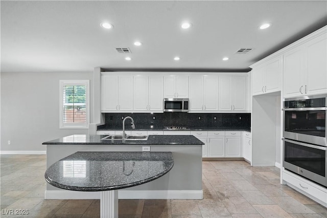 kitchen with appliances with stainless steel finishes, visible vents, decorative backsplash, and a sink