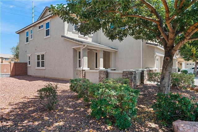 view of side of home featuring stucco siding and fence