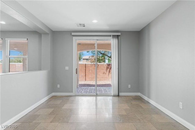 spare room with a wealth of natural light, visible vents, and baseboards
