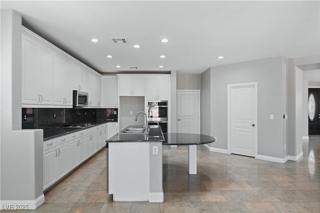kitchen with stainless steel appliances, stone tile flooring, a sink, baseboards, and visible vents