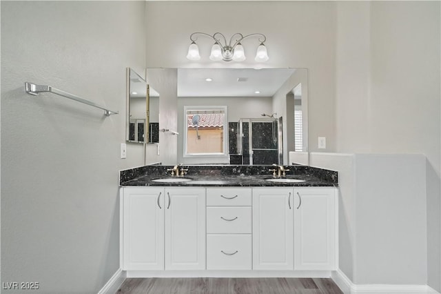 full bathroom featuring baseboards, a stall shower, wood finished floors, and a sink