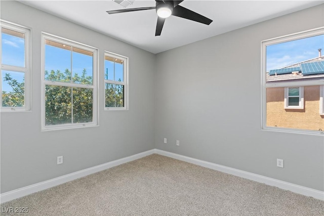 carpeted empty room with a healthy amount of sunlight, ceiling fan, and baseboards