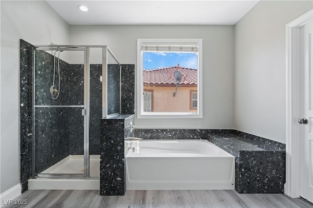 bathroom with a bath, wood finished floors, and a stall shower